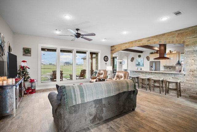 living room featuring beam ceiling, ceiling fan, and light wood-type flooring