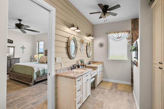 bathroom with vanity, hardwood / wood-style flooring, ceiling fan, and wooden walls