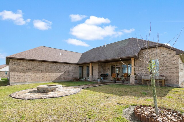 rear view of property featuring a patio area, a yard, and an outdoor fire pit