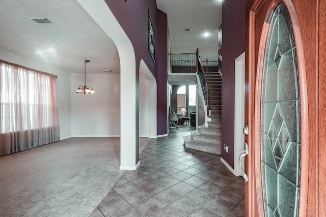 carpeted entryway featuring an inviting chandelier