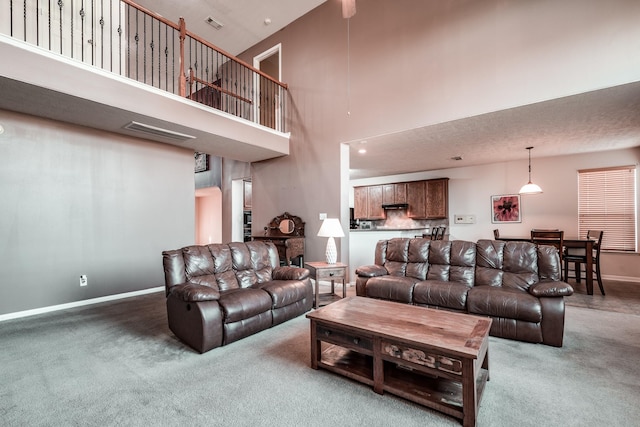 carpeted living room featuring a towering ceiling