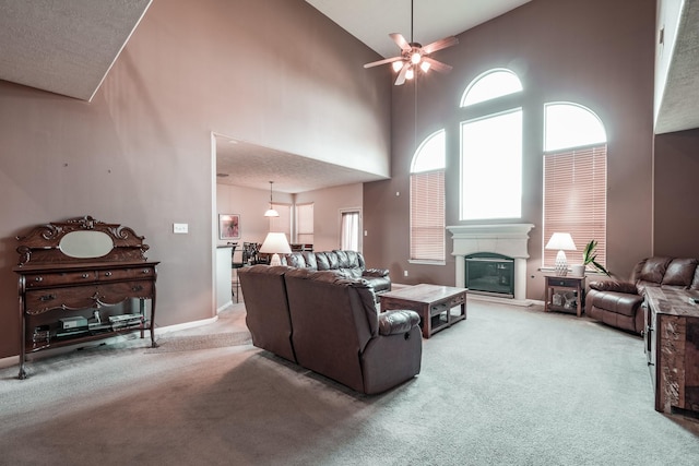 carpeted living room featuring a textured ceiling, ceiling fan, and a high ceiling