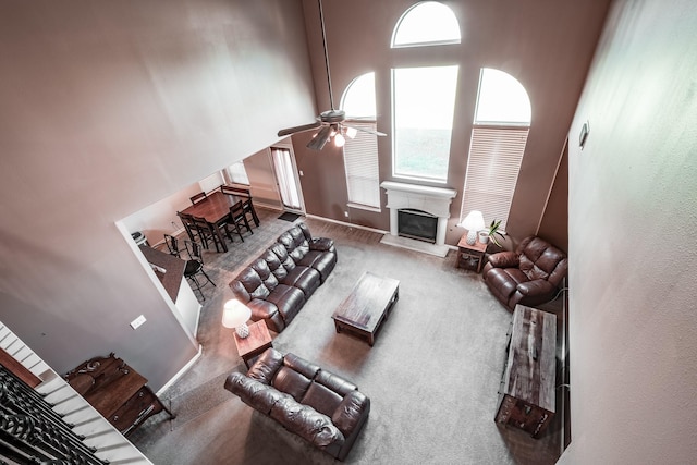 carpeted living room featuring a towering ceiling and ceiling fan