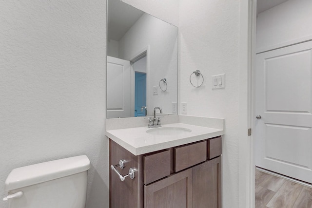 bathroom with hardwood / wood-style floors, vanity, and toilet