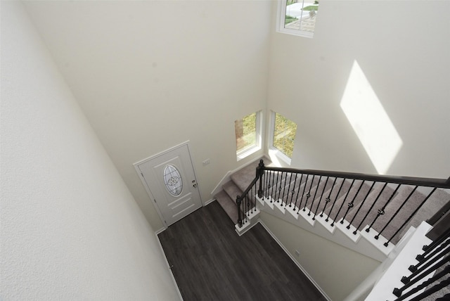 stairs with wood-type flooring and a high ceiling