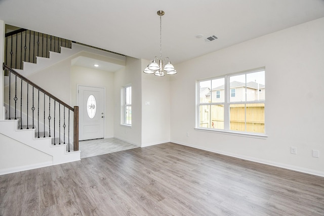 foyer featuring plenty of natural light, wood-type flooring, and an inviting chandelier