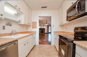 kitchen with sink, white cabinets, stainless steel appliances, and light hardwood / wood-style floors