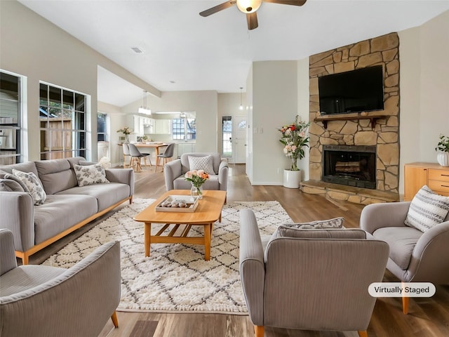 living room with ceiling fan, a fireplace, lofted ceiling with beams, and hardwood / wood-style flooring