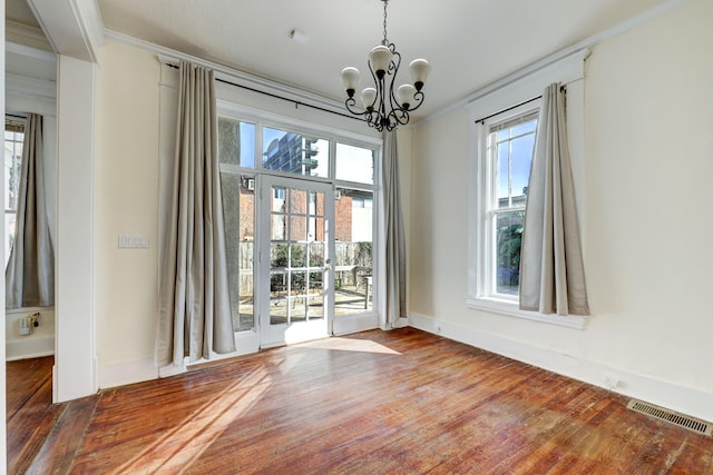 interior space featuring hardwood / wood-style flooring, ornamental molding, and an inviting chandelier