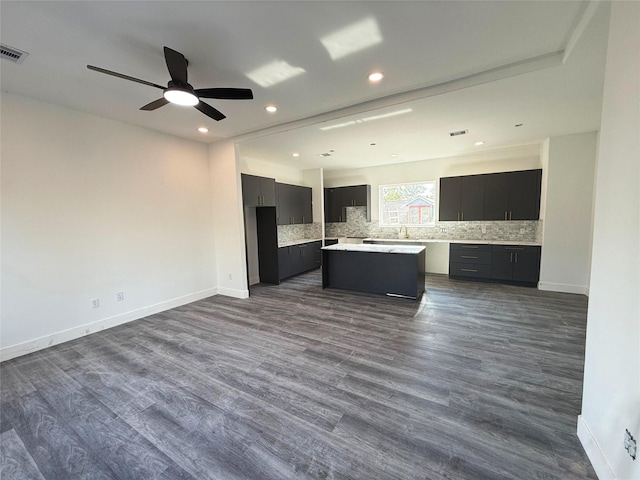 kitchen with tasteful backsplash, a kitchen island, ceiling fan, and dark wood-type flooring