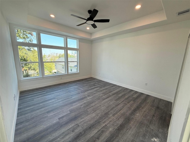 spare room featuring ceiling fan, a raised ceiling, and dark wood-type flooring