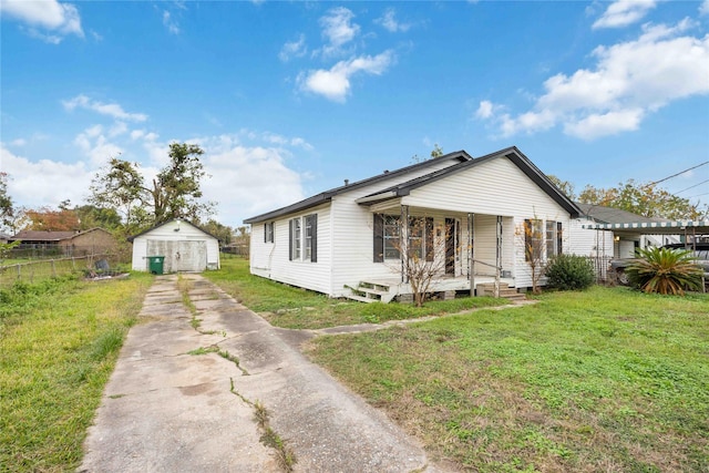 view of front facade featuring a front yard, an outbuilding, and covered porch