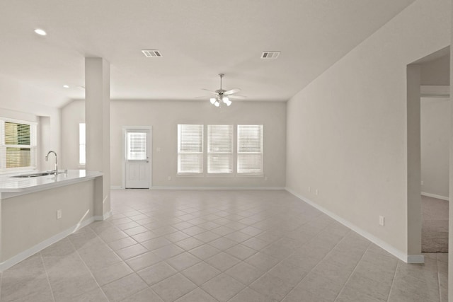 unfurnished living room featuring light tile patterned floors, ceiling fan, and sink