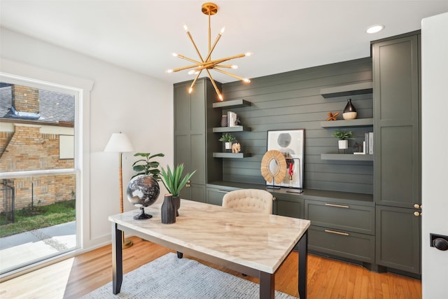 office space featuring a chandelier, light hardwood / wood-style floors, and wood walls