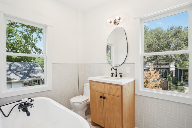 bathroom featuring a bathing tub, vanity, tile walls, and toilet