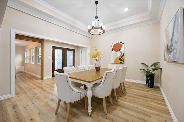 dining room with an inviting chandelier, french doors, a raised ceiling, light wood-type flooring, and ornamental molding