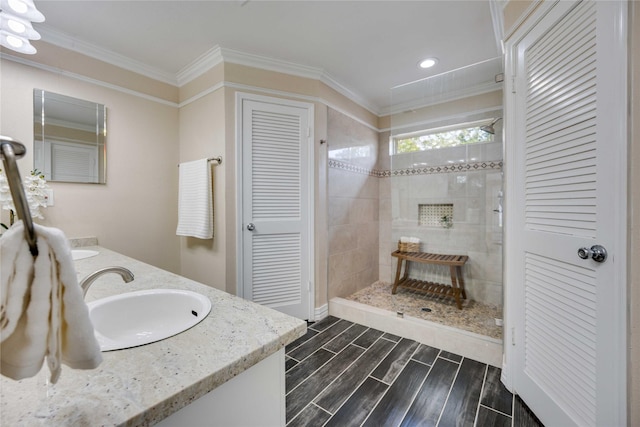 bathroom with a tile shower, vanity, and ornamental molding