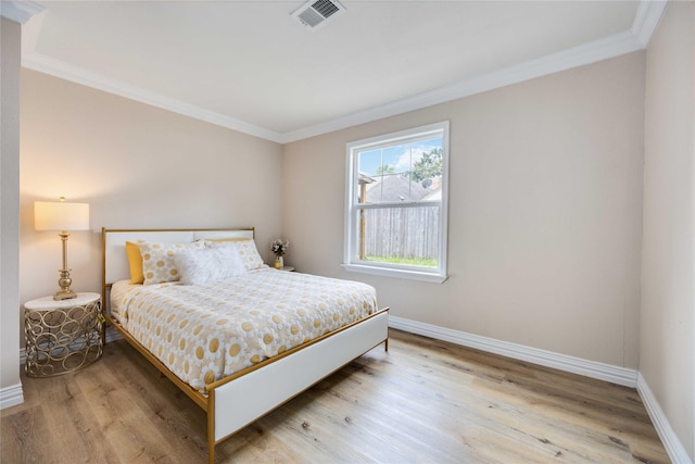 bedroom with light wood-type flooring and crown molding