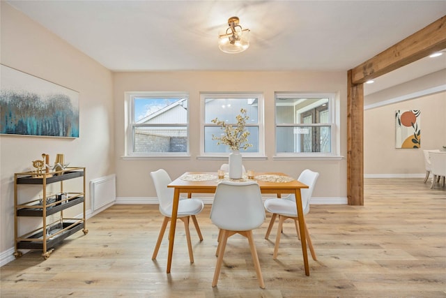 dining area with beam ceiling and light hardwood / wood-style flooring