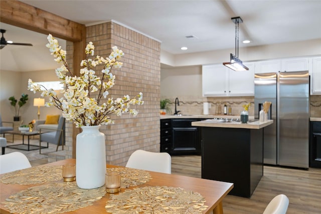 kitchen with ceiling fan, a center island, backsplash, stainless steel fridge, and white cabinets