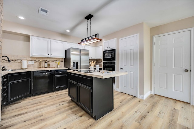 kitchen featuring decorative backsplash, sink, black appliances, pendant lighting, and a kitchen island