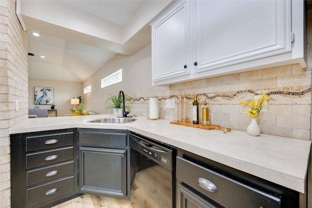 kitchen with sink, white cabinetry, black dishwasher, and vaulted ceiling