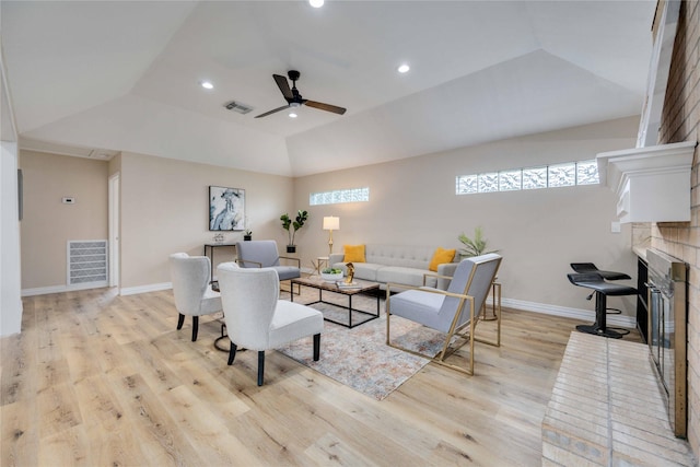 living room featuring a raised ceiling, ceiling fan, a fireplace, light hardwood / wood-style floors, and lofted ceiling