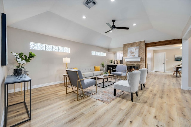 living room with a fireplace, light hardwood / wood-style floors, vaulted ceiling, and ceiling fan