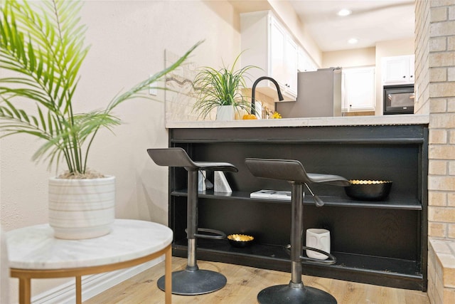 interior details featuring hardwood / wood-style flooring, stainless steel fridge, and black microwave