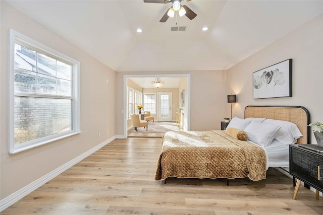 bedroom featuring lofted ceiling, light hardwood / wood-style flooring, and ceiling fan with notable chandelier