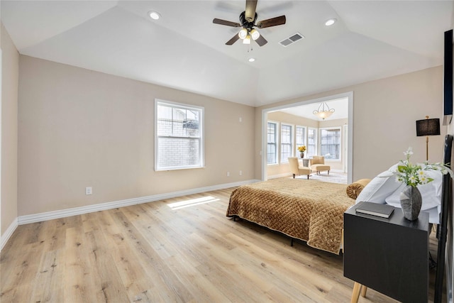 bedroom featuring ceiling fan, a raised ceiling, light wood-type flooring, and vaulted ceiling