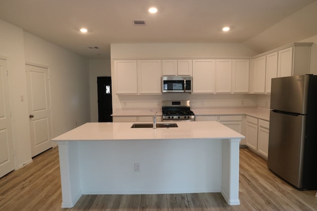 kitchen with stainless steel appliances, a kitchen island with sink, sink, light hardwood / wood-style floors, and white cabinetry