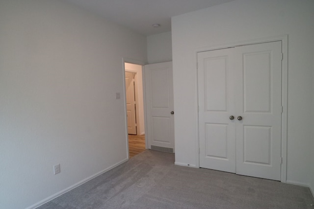 unfurnished bedroom featuring light carpet and a closet