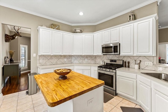 kitchen featuring a center island, stainless steel appliances, white cabinetry, and crown molding