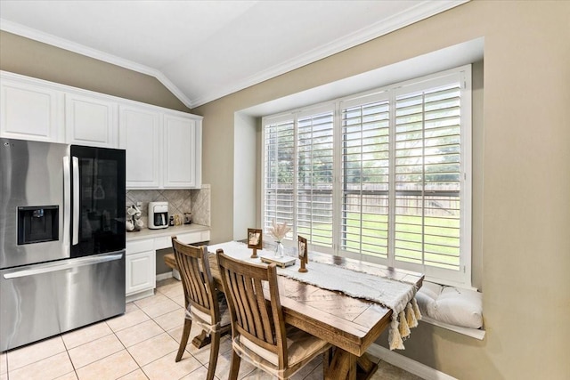 dining area with plenty of natural light, light tile patterned floors, ornamental molding, and vaulted ceiling