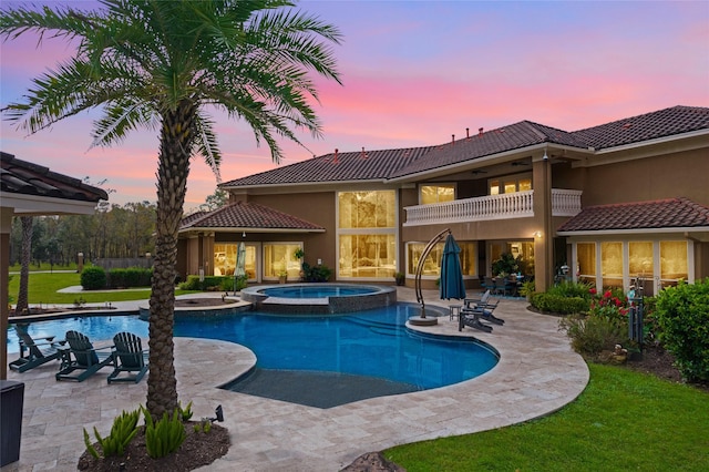 pool at dusk with a patio area and an in ground hot tub