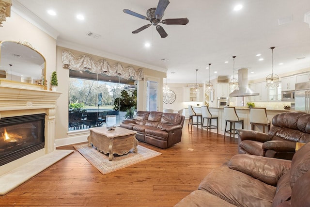 living room with light wood-type flooring, ceiling fan, and crown molding