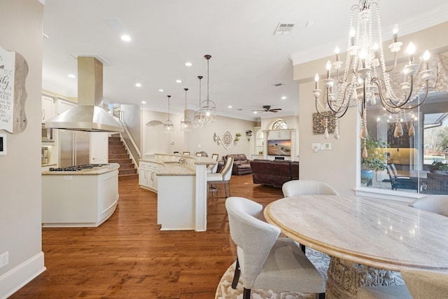 kitchen featuring ceiling fan, hanging light fixtures, dark hardwood / wood-style floors, island exhaust hood, and a kitchen island