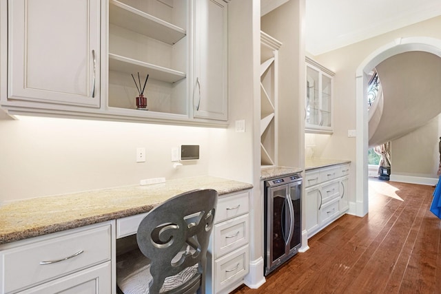 home office with built in desk, beverage cooler, and dark wood-type flooring