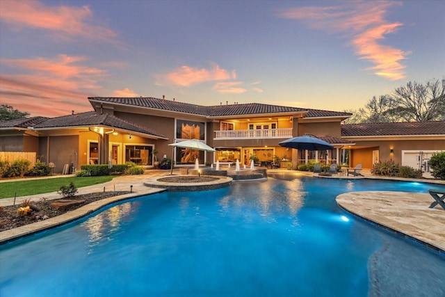 pool at dusk featuring an in ground hot tub and a patio