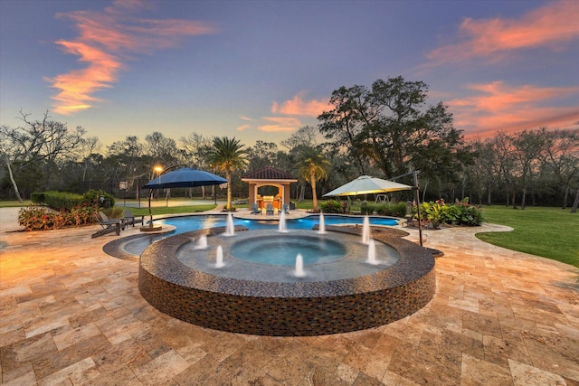 pool at dusk with a jacuzzi, a gazebo, pool water feature, and a yard