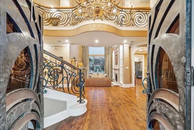 foyer entrance featuring hardwood / wood-style flooring, a towering ceiling, and ornamental molding