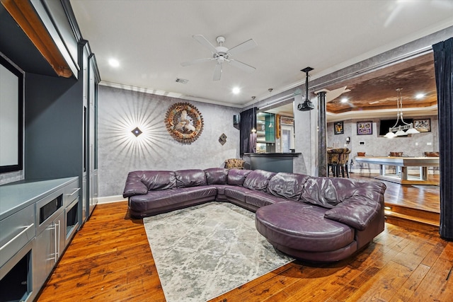 living room featuring ceiling fan, wood-type flooring, and ornamental molding