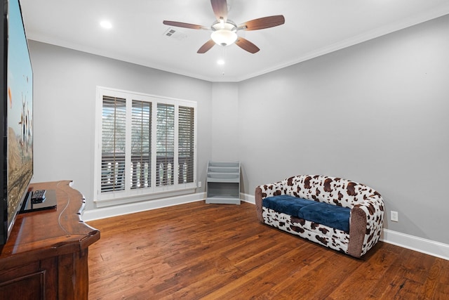 living area featuring hardwood / wood-style floors, ceiling fan, and crown molding