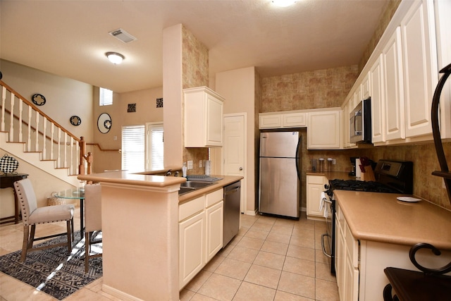 kitchen featuring sink, light tile patterned floors, decorative backsplash, white cabinets, and appliances with stainless steel finishes