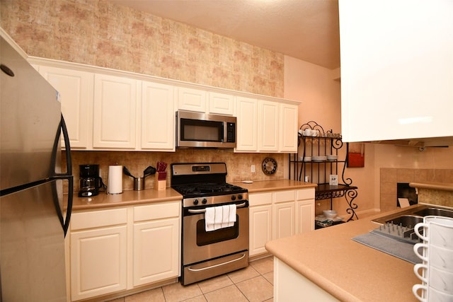 kitchen featuring white cabinets, sink, light tile patterned floors, and stainless steel appliances