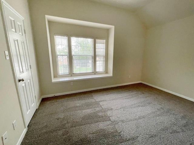 carpeted empty room featuring vaulted ceiling