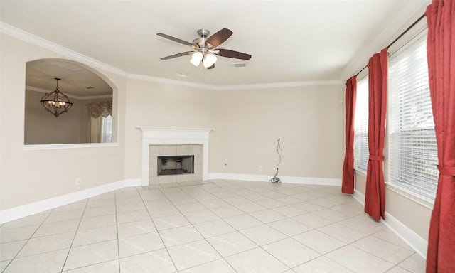 unfurnished living room with ceiling fan with notable chandelier, light tile patterned flooring, crown molding, and a tiled fireplace