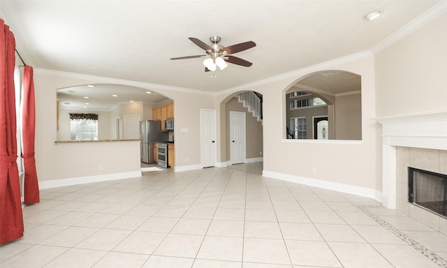 unfurnished living room featuring ceiling fan, light tile patterned flooring, crown molding, and a tile fireplace