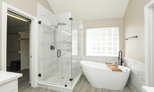 bathroom featuring vanity, lofted ceiling, hardwood / wood-style flooring, shower with separate bathtub, and tile walls